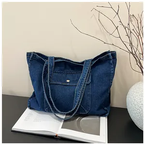 Detailansicht der dunkelblauen Denim-Tragetasche mit Vordertasche und Metallschnallenverschluss