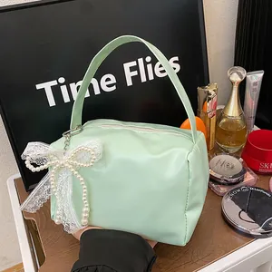 Detail of mint green cosmetic bag featuring a lace bow and pearls on a dressing table