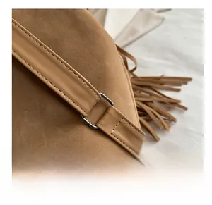 Detail of vintage brown suede backpack featuring silver metal ring buckle and long tassels