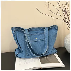Detail der blauen Denim-Einkaufstasche mit kleiner Tasche und goldener Metallknopfschnalle