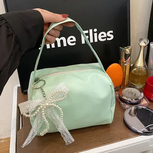 Detail of mint green leather bridesmaid pouch with lace bow and pearl charm