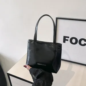 Dettaglio borsa a mano nera lucida in pelle verniciata con scritta Fashion and Bags argento