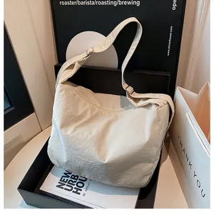 Close-up of beige wide-strap crossbody tote bag with soft nylon texture and silver buckle