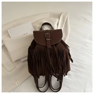 Detail of vintage dark brown suede backpack featuring long decorative fringe and magnetic flap