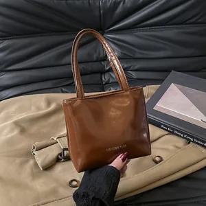 Dettaglio di una borsa a trapezio in vernice marrone con scritta FASHION & BAGS