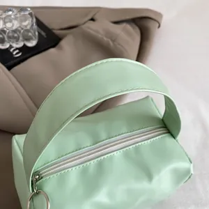 Detail view of mint green PU leather handbag with smooth texture and metal zipper