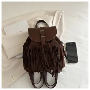Close-up of brown suede tassel backpack with vintage metal buckle and fringe details