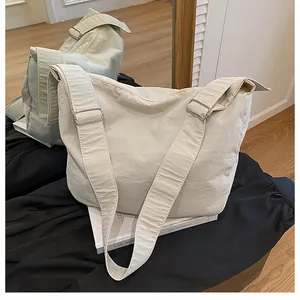 Detail showing high-capacity canvas crossbody bags in cream and sage green on a book