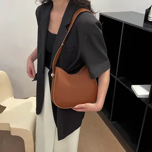 Bruine lederen zadeltas getoond op een model in een minimalistische moderne binnenruimte