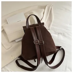 Detailed close-up of dark brown vintage backpack with suede texture and metal buckles