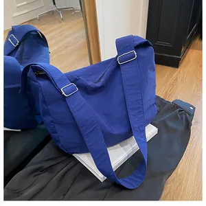 Detail of royal blue crescent bag showing wide shoulder strap and silver metal buckle