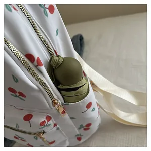 Detail of white cherry print backpack showing side pocket with a mini folded umbrella