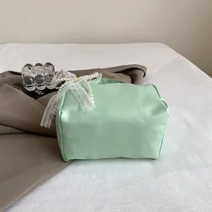 Detail of mint green handbag with pearl handle and white lace bow decoration
