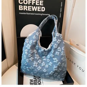Dettaglio borsa shopper azzurra con trama floreale in rilievo 3D e finitura in tessuto