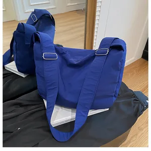 Detail view of royal blue nylon crossbody bag with wide strap and silver metal buckle