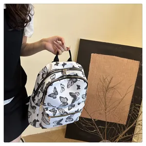 Detail view of stylish white backpack with black butterfly print and gold zippers