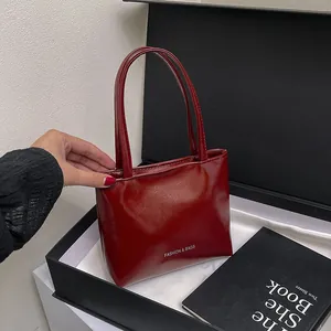 Dettaglio borsa a mano rosso vino lucido in scatola regalo con finitura a specchio