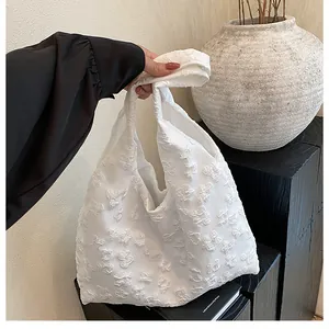 Dettaglio di borsa tote bianca con trama floreale 3D e rifiniture in pizzo eleganti