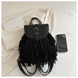 Close-up of black fringe backpack with suede texture and metal buckle on flat lay background