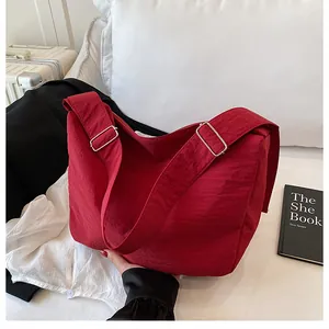 Close-up of red nylon crossbody bag with pleated texture and silver metal buckle