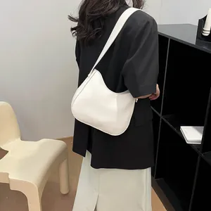 Minimalistische witte zadeltas getoond op een model in een moderne kantooromgeving