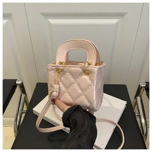 Macro view of the pink quilted leather texture and gold hardware on the mini bag