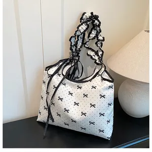 Detail of white canvas bag with black bow print and pleated ruffle shoulder straps
