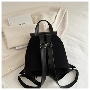 Detail of vintage black suede backpack with slim leather straps on a beige blazer