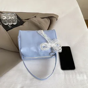 Close-up of light blue handbag with delicate lace bow and white pearl accents