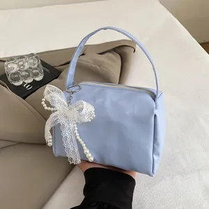 Close-up of light blue handbag featuring white lace bow and faux pearl decorative charm