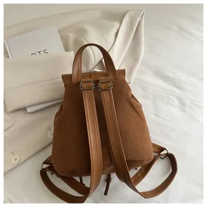 Retro brown suede backpack detail with tassel and smooth leather straps on a white blazer