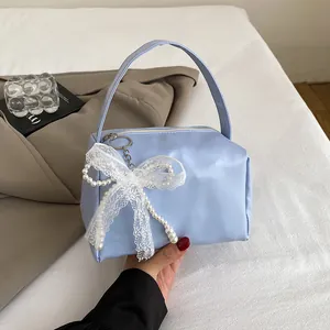 Detail of light blue PU handbag with delicate lace bow and pearl charm ornament