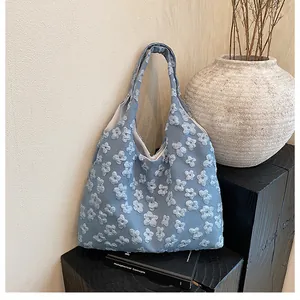Dettaglio di borsa tote azzurra con ricamo floreale 3D e consistenza del tessuto