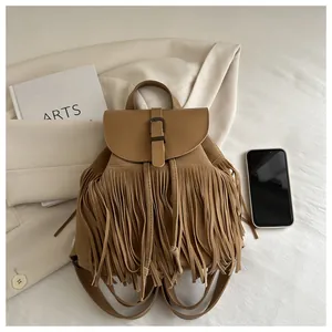 Flat lay of khaki tassel backpack with leather flap and drawstring closure on white fabric