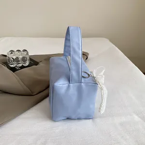 Detail of light blue PU leather handbag featuring a pearl butterfly lace charm