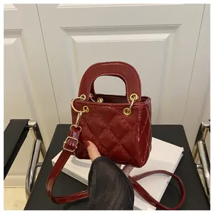 Macro detail of dark red quilted lacquer leather bag with elegant gold-tone hardware