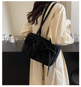 Détail d'un grand sac à bandoulière noir avec nœud papillon et design fourre-tout chic