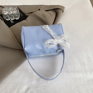 Detail of light blue handbag with white lace bow, pearl accents and silver metal ring