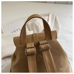 Detail of adjustable metal buckles and suede texture on a vintage brown backpack