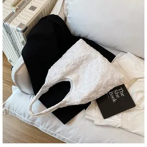 Dettaglio della borsa tote bianca con elegante trama in pizzo floreale 3D e manico sobrio
