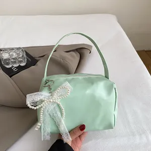 Detailed view of mint green handbag with elegant pearl lace bow and soft leather texture