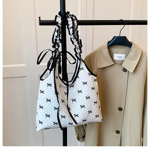 Detail of white canvas shoulder bag with black polka dots and pleated ruffle handles