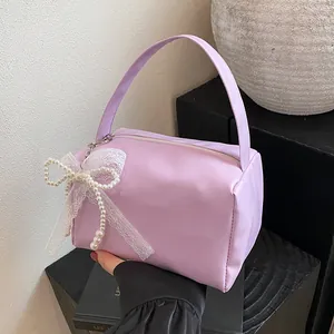 Detail of lavender handbag featuring delicate white lace and pearl bow charms on handle