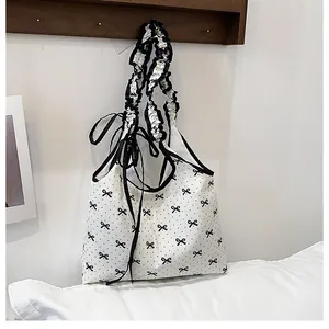Detailed view of white canvas shoulder bag with black polka dots and ruffled handle straps