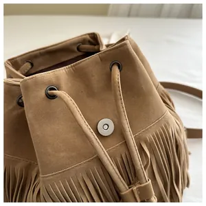 Close-up of brown suede backpack showing fringe tassels and magnetic snap button