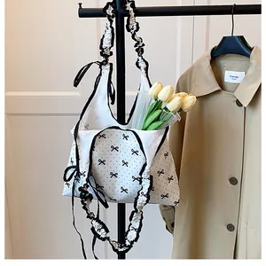 Detail of sweet canvas tote bag showing black polka dots, bow patterns and ruffled edges