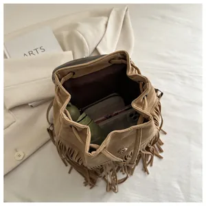 Detail view of brown suede bucket bag with tassels showing spacious interior for essentials