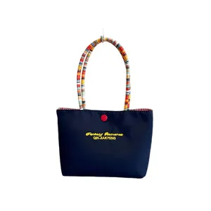 Navy blue tote bag with yellow embroidery and colorful braided handles on white background