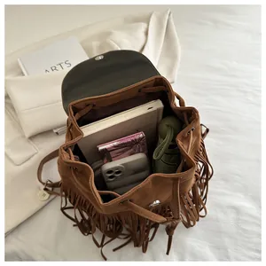 Brown suede tassel backpack showing spacious interior with books and umbrella