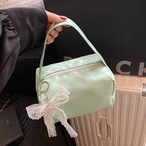 Detail of light green PU leather handbag featuring lace bow and pearl pendant charm